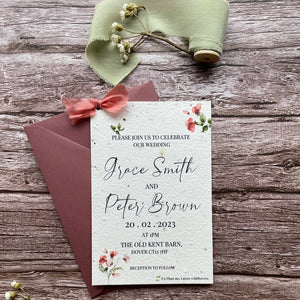 personalised plantable wedding invitations in sweet pea theme, showing front view with colour matched envelope, floral design on wooden background