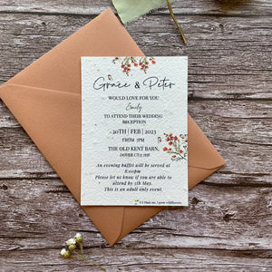 plantable evening guest wedding invitations in burnt orange theme, showing front view with colour matched envelope, floral design on wooden background