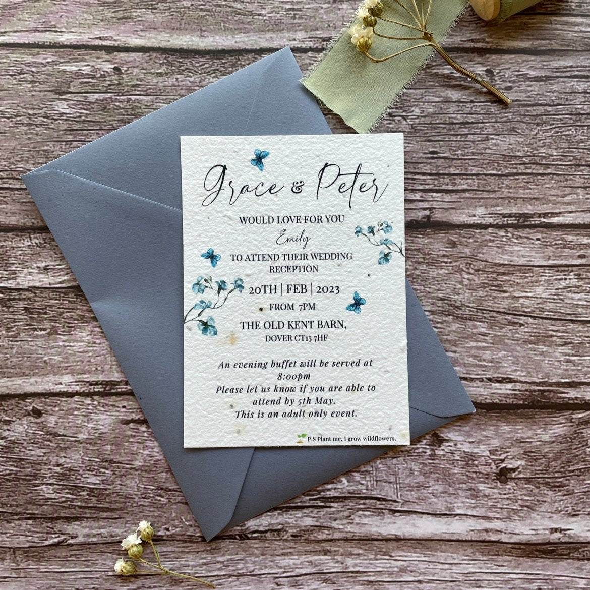 plantable evening guest wedding invitations in dusty blue theme, showing front view with colour matched envelope, floral design on wooden background