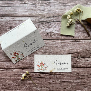 plantable seed paper wedding guest place cards in burnt orange theme, showing flat and standing views, floral design on wooden background.