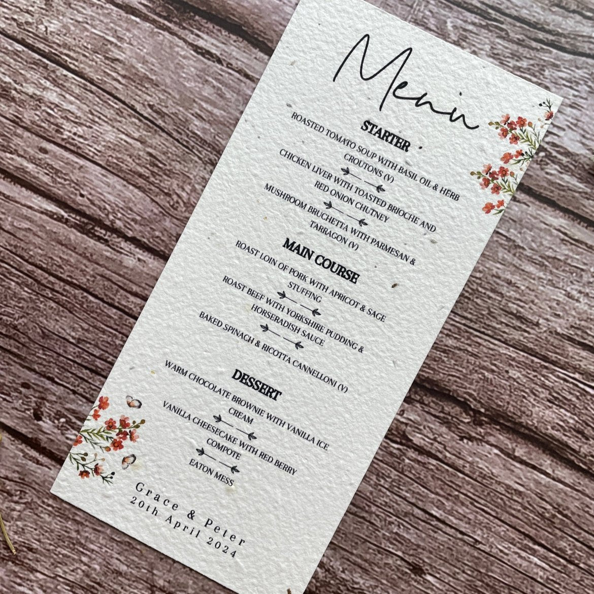 plantable seed paper wedding menu card in burnt orange theme, showing an angled view, floral design on wooden background, eco-friendly