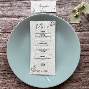 plantable seed paper wedding menu card in lilac theme, placed on a blue plate, floral design on wooden background, eco-friendly