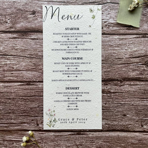 plantable seed paper wedding menu card in spring green theme, showing a close-up front view, floral design on wooden background, eco-friendly