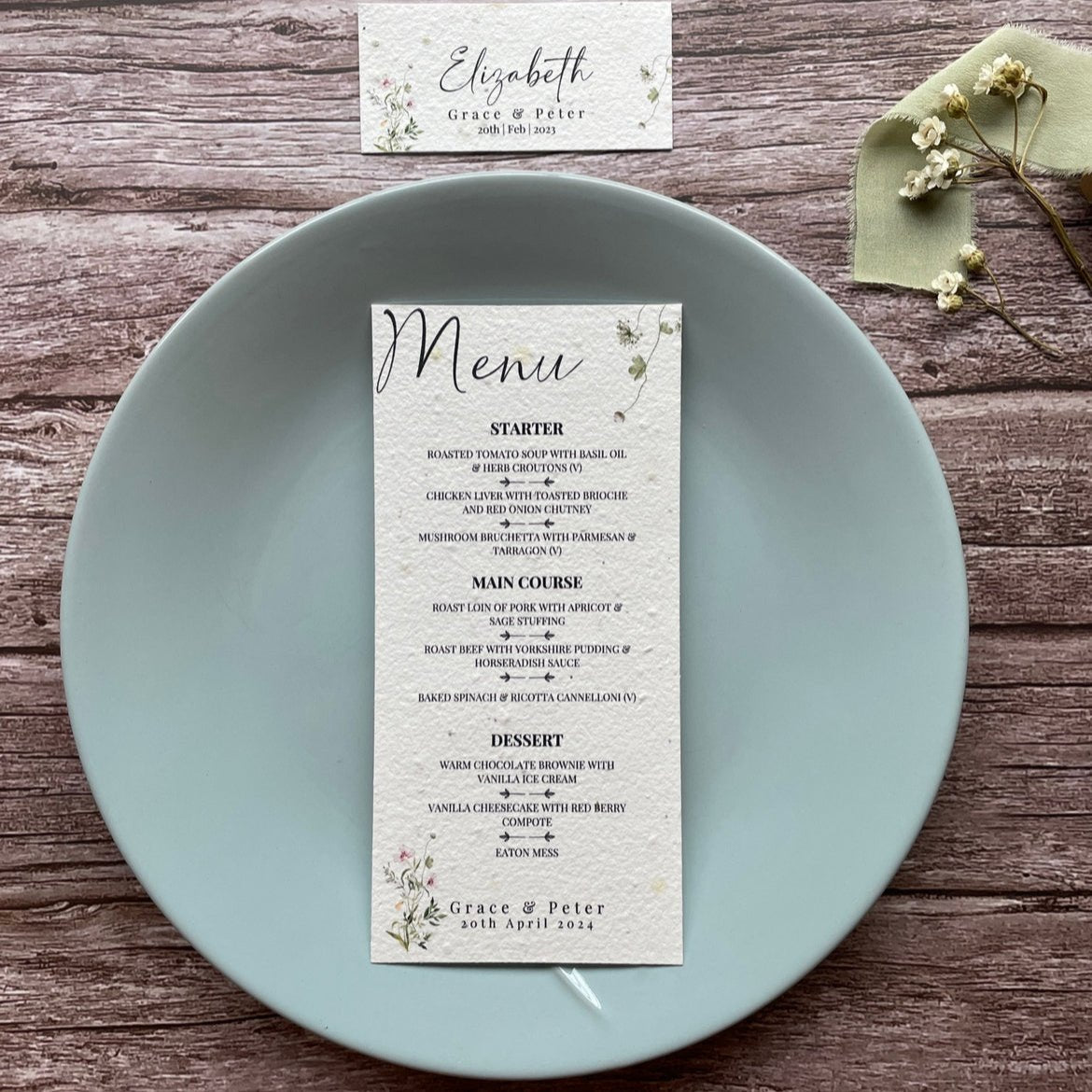 plantable seed paper wedding menu card in spring green theme, placed on a blue plate, floral design on wooden background, eco-friendly