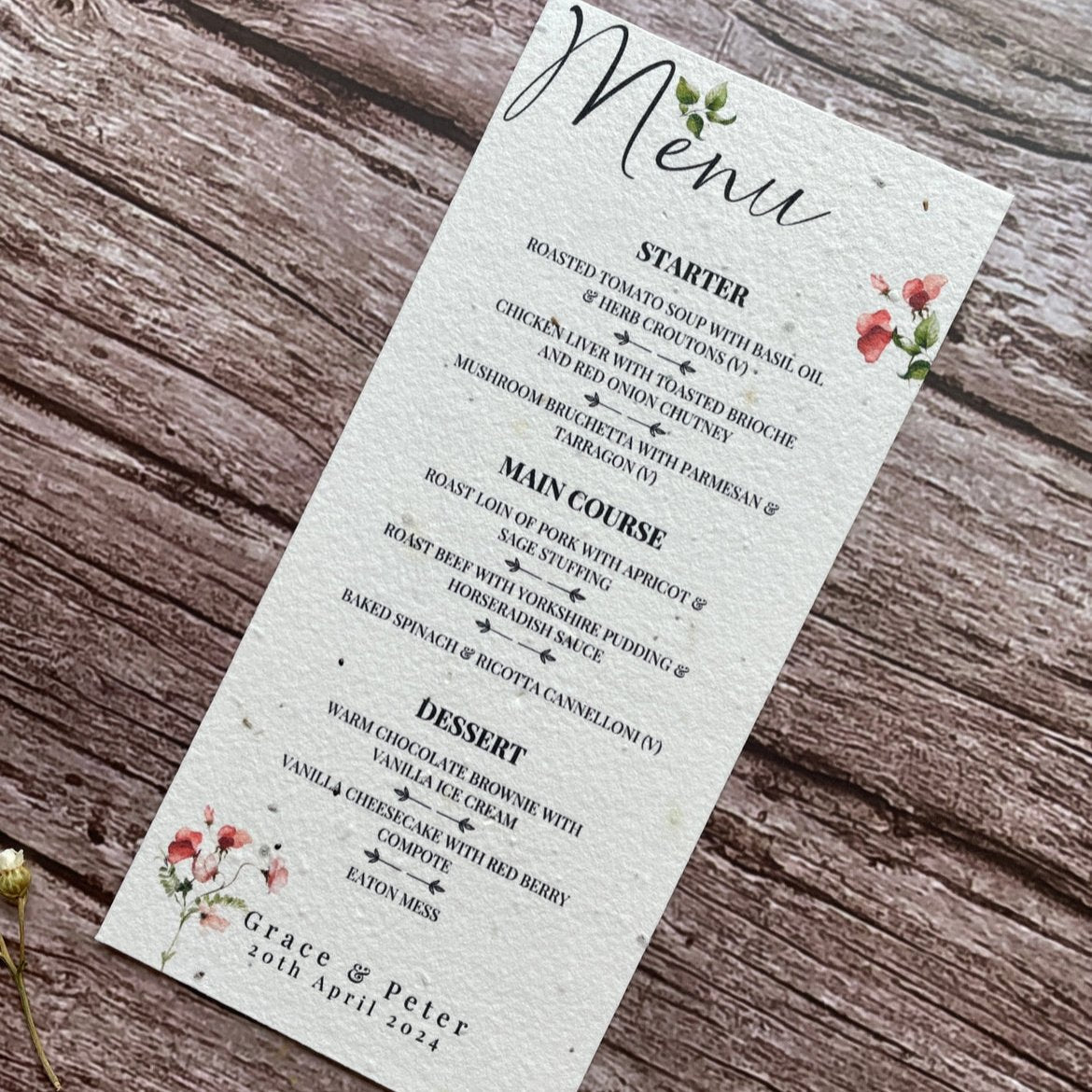 plantable seed paper wedding menu card in sweet pea theme, showing an angled view, floral design on wooden background, eco-friendly