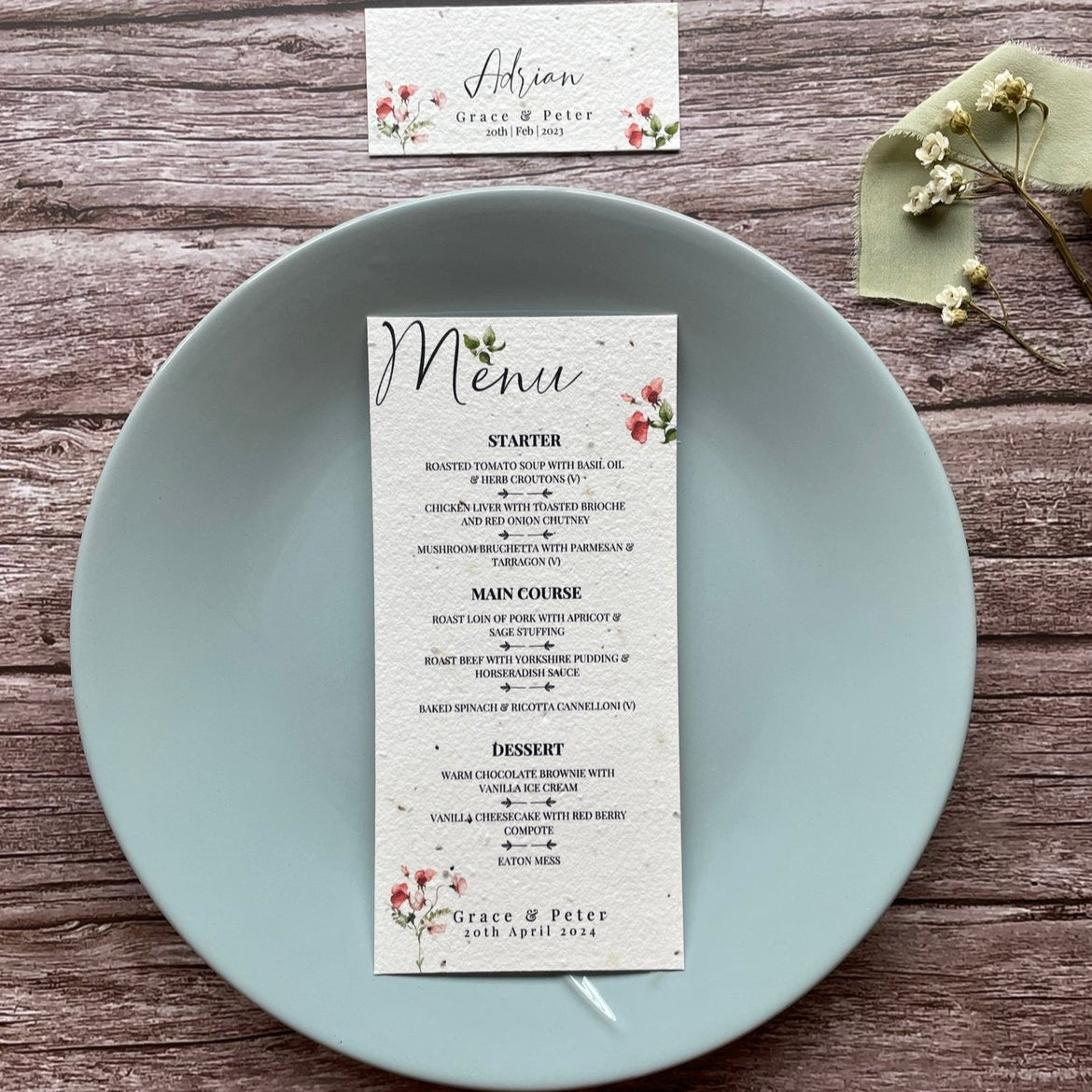 plantable seed paper wedding menu card in sweet pea theme, placed on a blue plate, floral design on wooden background, eco-friendly