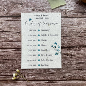 plantable seed paper wedding order of service card in dusty blue theme, showing front view, floral design on wooden background, eco-friendly