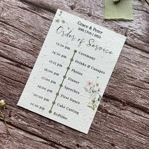 plantable seed paper wedding order of service card in spring green theme, showing angled right view, floral design on wooden background, eco-friendly