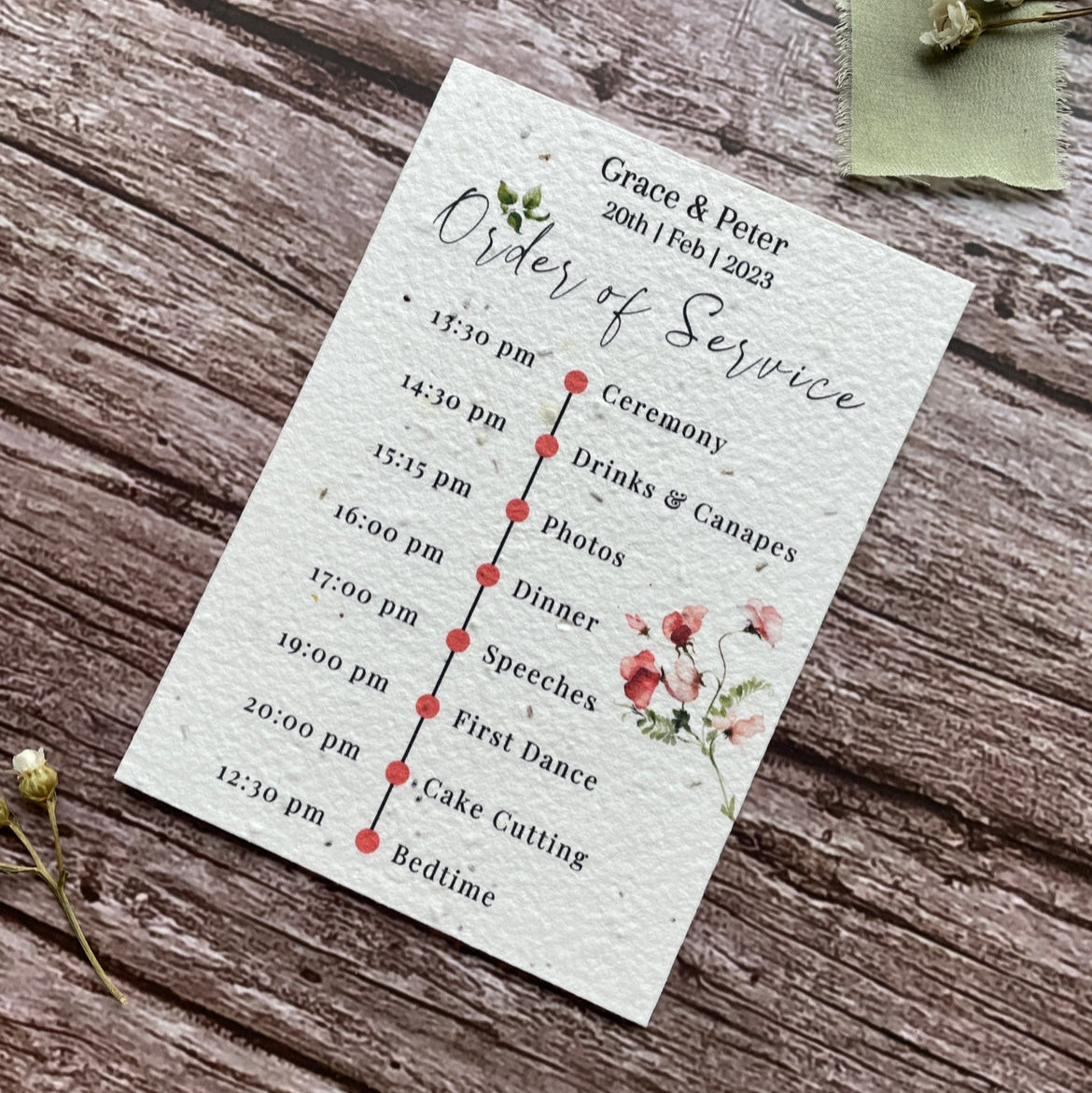 plantable seed paper wedding order of service card in sweet pea theme, showing angled right view, floral design on wooden background, eco-friendly