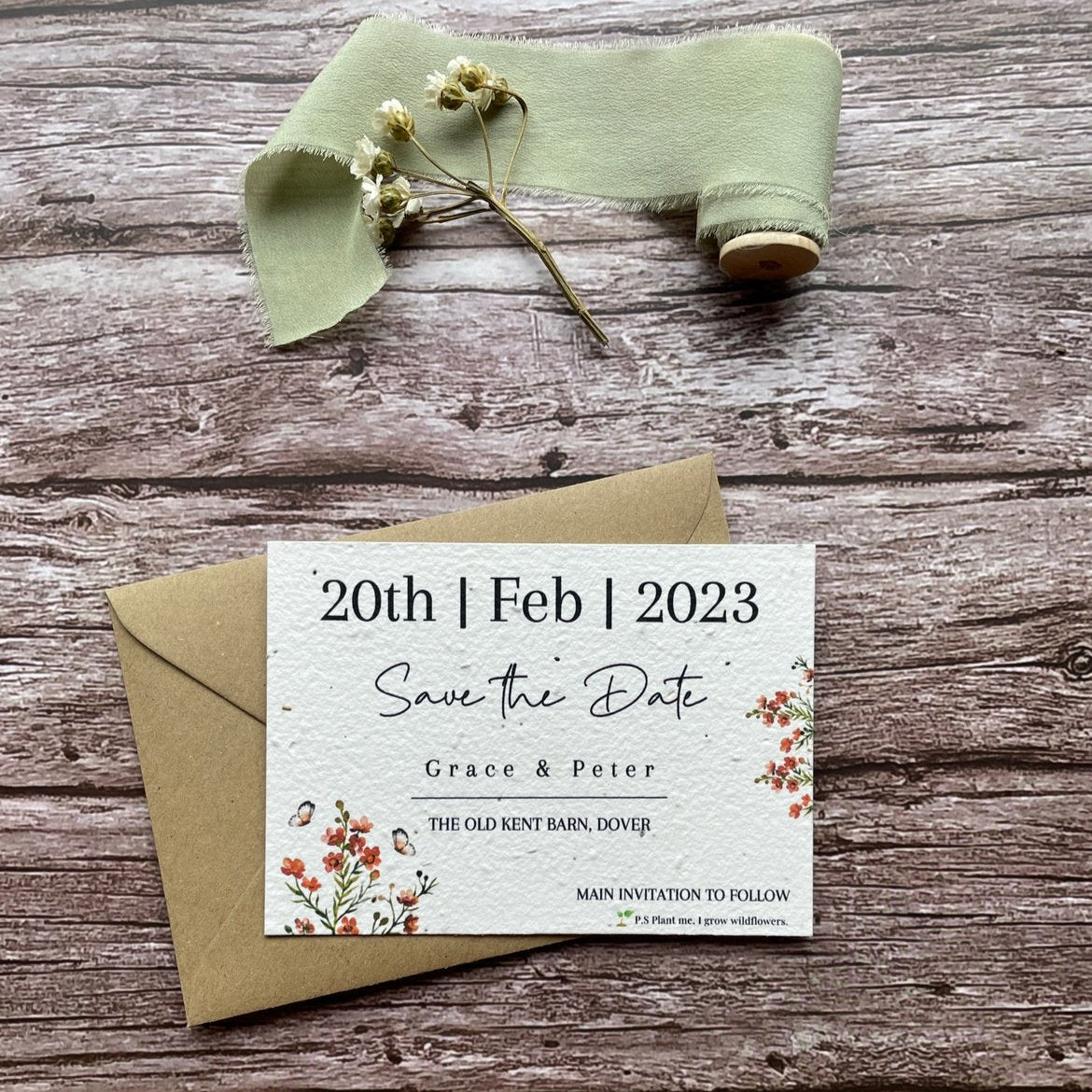 plantable seed paper wedding save the date card in burnt orange theme, with eco-friendly brown kraft envelope, floral design on wooden background