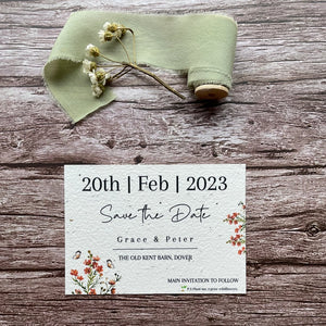 plantable seed paper wedding save the date card in burnt orange theme, showing front close-up view, floral design on wooden background, eco-friendly