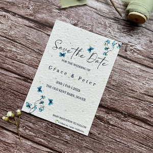 plantable seed paper wedding save the date card in dusty blue theme, showing angled view, floral design on wooden background, eco-friendly