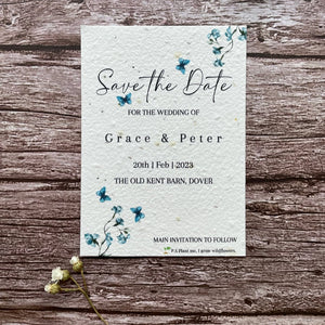 plantable seed paper wedding save the date card in dusty blue theme, showing front close-up view, floral design on wooden background, eco-friendly