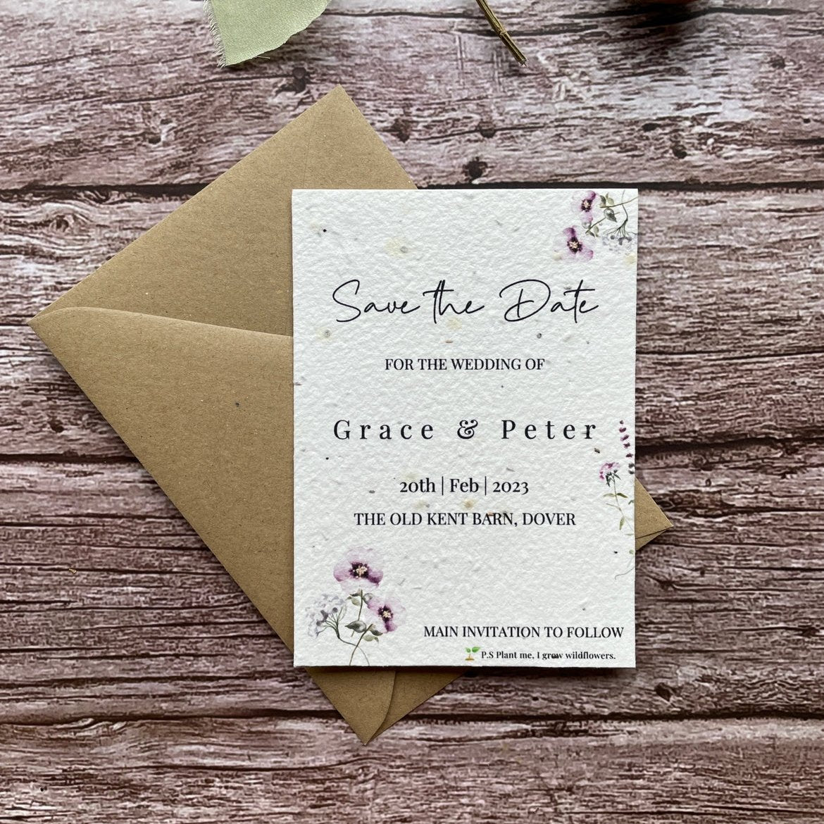 plantable seed paper wedding save the date card in lilac theme, shown with eco-friendly brown kraft envelope, floral design on wooden background.