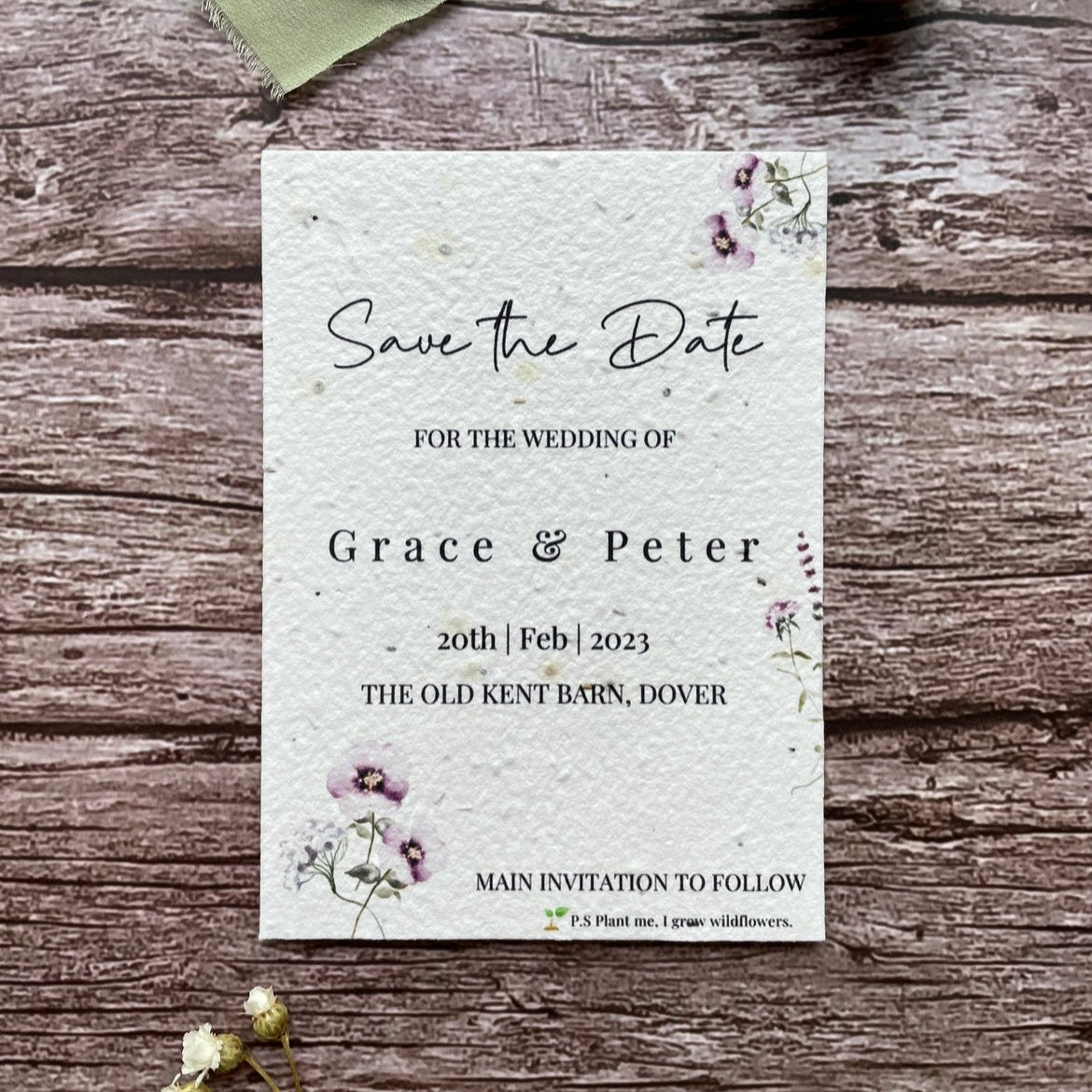 plantable seed paper wedding save the date card in lilac theme, showing front close-up view, floral design on wooden background, eco-friendly