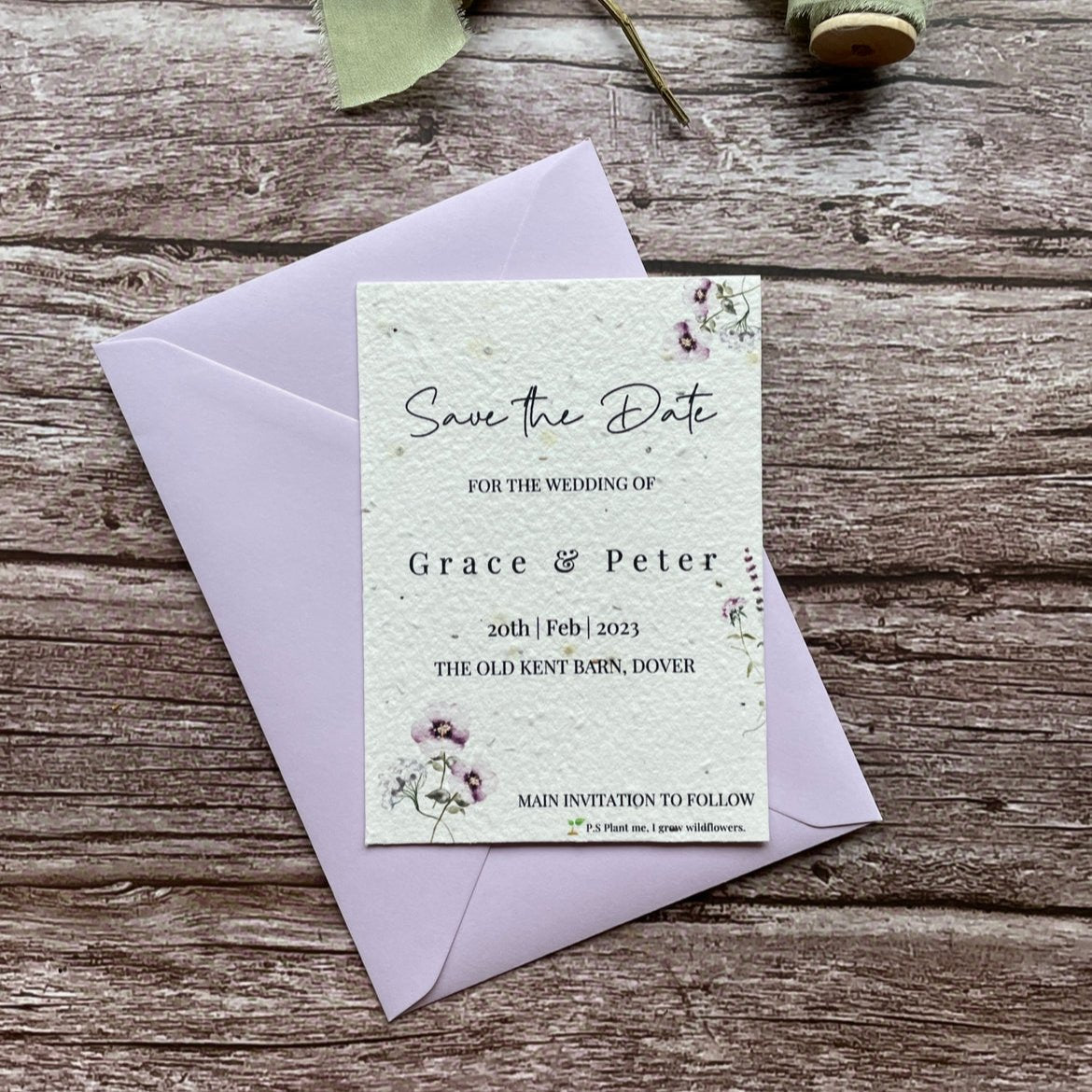 plantable seed paper wedding save the date card in lilac theme, shown with theme colour matched envelope, floral design on wooden background