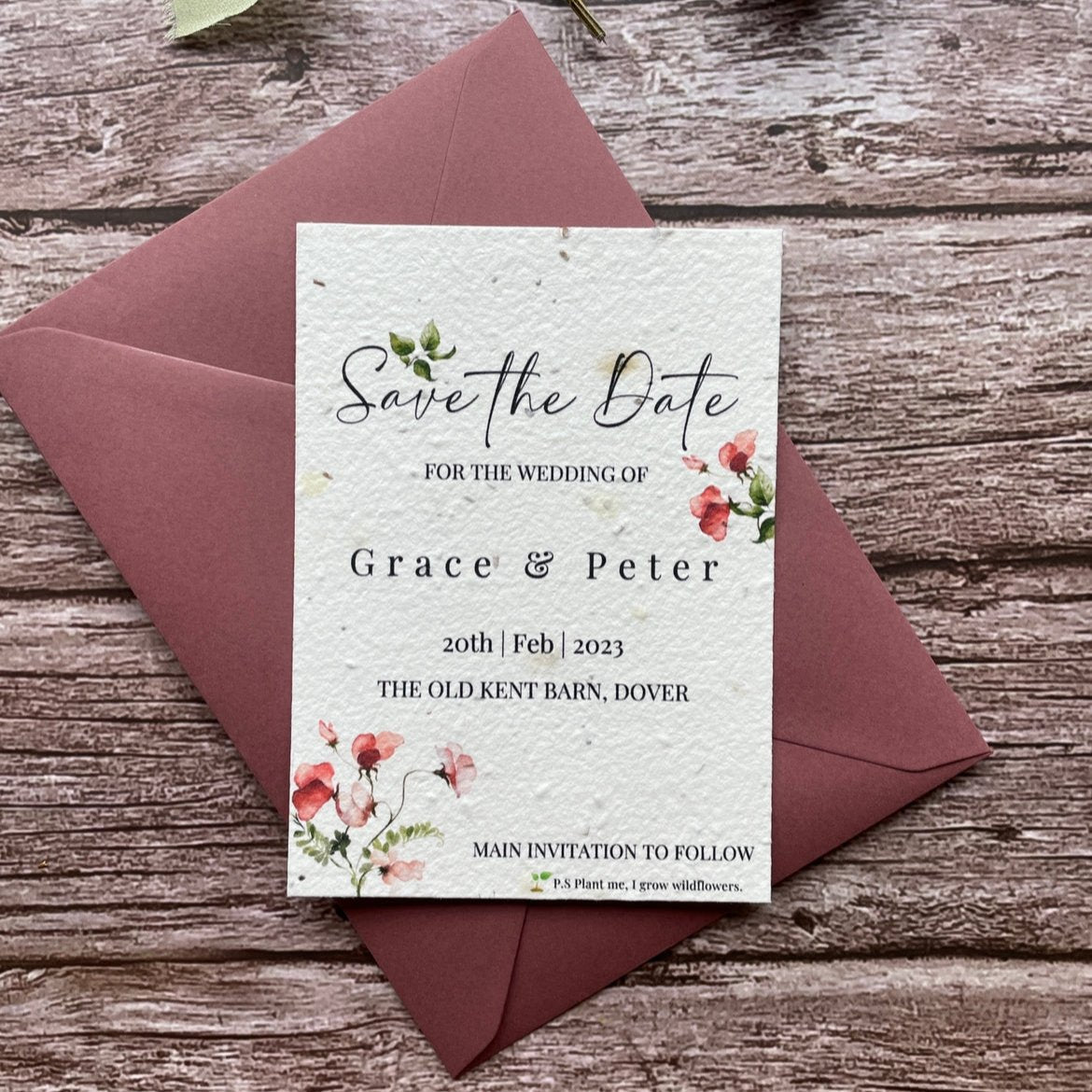 plantable seed paper wedding save the date card in sweet pea theme, shown with theme colour matched envelope, floral design on wooden background.