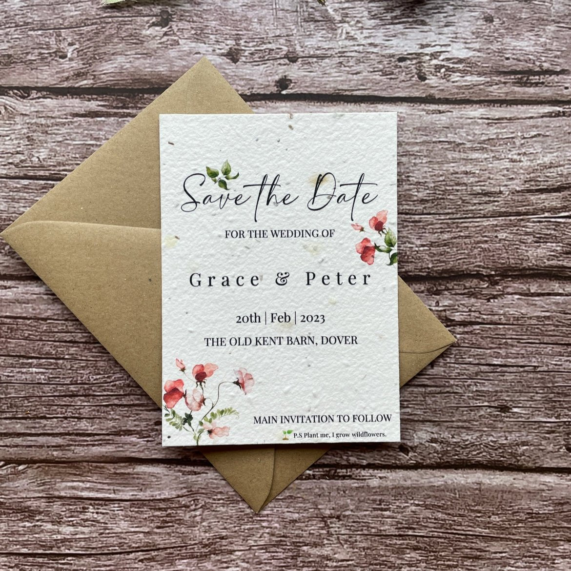 plantable seed paper wedding save the date cards in sweet pea theme, front view with eco-friendly brown kraft envelope, floral design on wooden background, alakartcreations