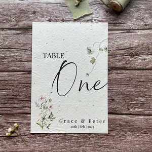 plantable seed paper wedding table number/name card in spring green theme, showing front view, floral design on wooden background, eco-friendly