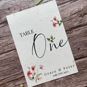 plantable seed paper wedding table number or name cards in sweet pea theme, angled left view with floral design on wooden background, eco-friendly, alakartcreations