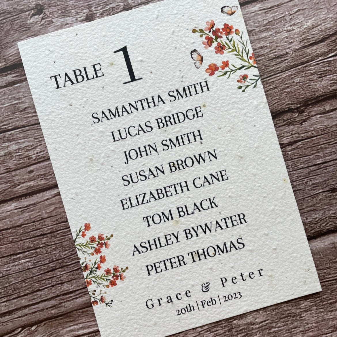 plantable seed paper wedding table seating plan in burnt orange theme, angled left view with floral design on wooden background, eco-friendly, alakartcreations