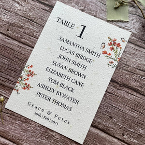 plantable seed paper wedding table seating plan in burnt orange theme, showing angled right view, floral design on wooden background, eco-friendly