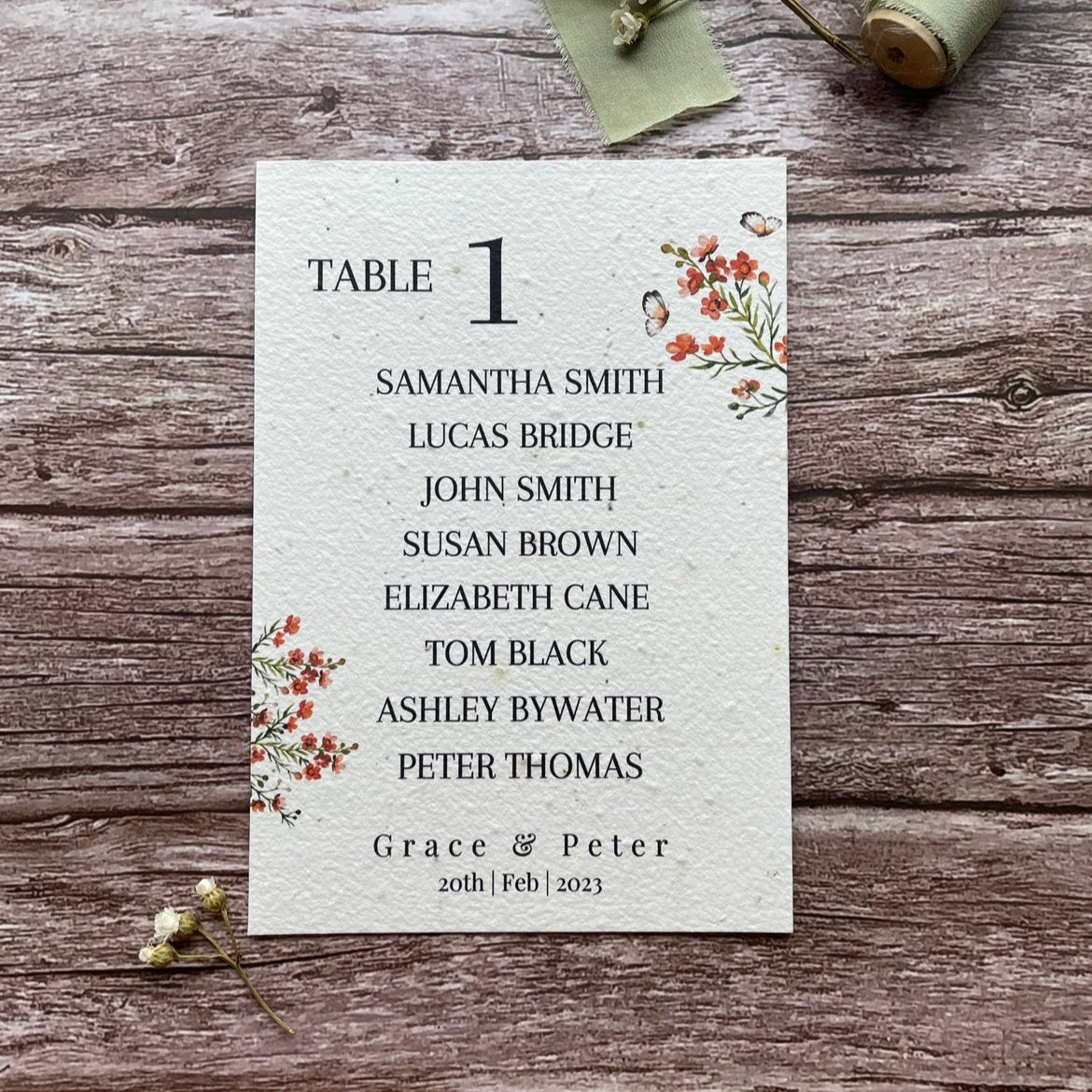 plantable seed paper wedding table seating plan in burnt orange theme, showing front view, floral design on wooden background, eco-friendly