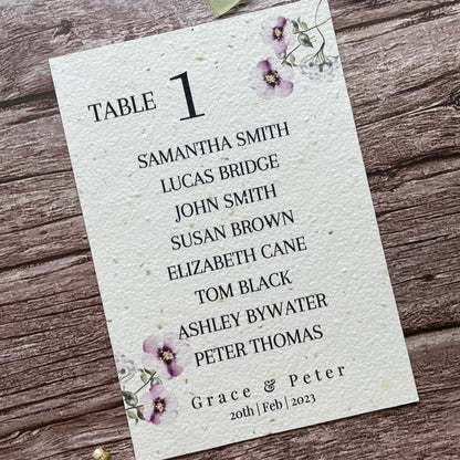 plantable seed paper wedding table seating plan in lilac theme, angled left view with floral design on wooden background, eco-friendly, alakartcreations