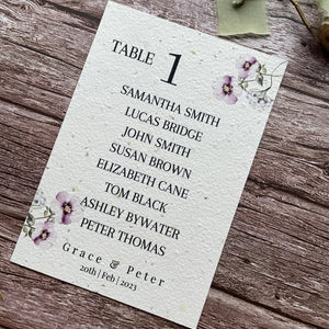 plantable seed paper wedding table seating plan in lilac theme, showing angled right view, floral design on wooden background, eco-friendly