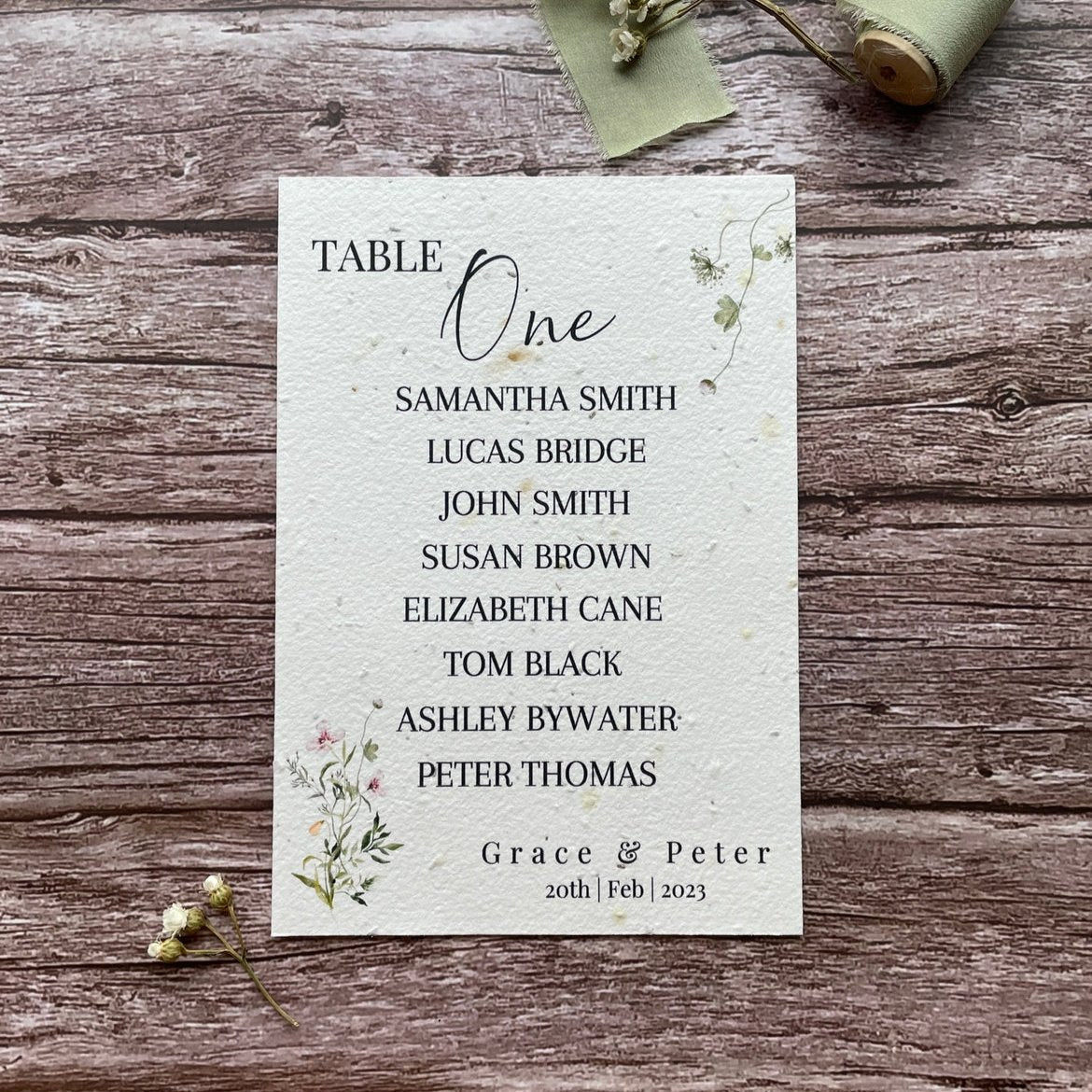 plantable seed paper wedding table seating plan in spring green theme, showing front view, floral design on wooden background, eco-friendly