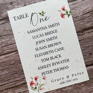 plantable seed paper wedding table seating plan in sweet pea theme, showing angled left view, floral design on wooden background, eco-friendly