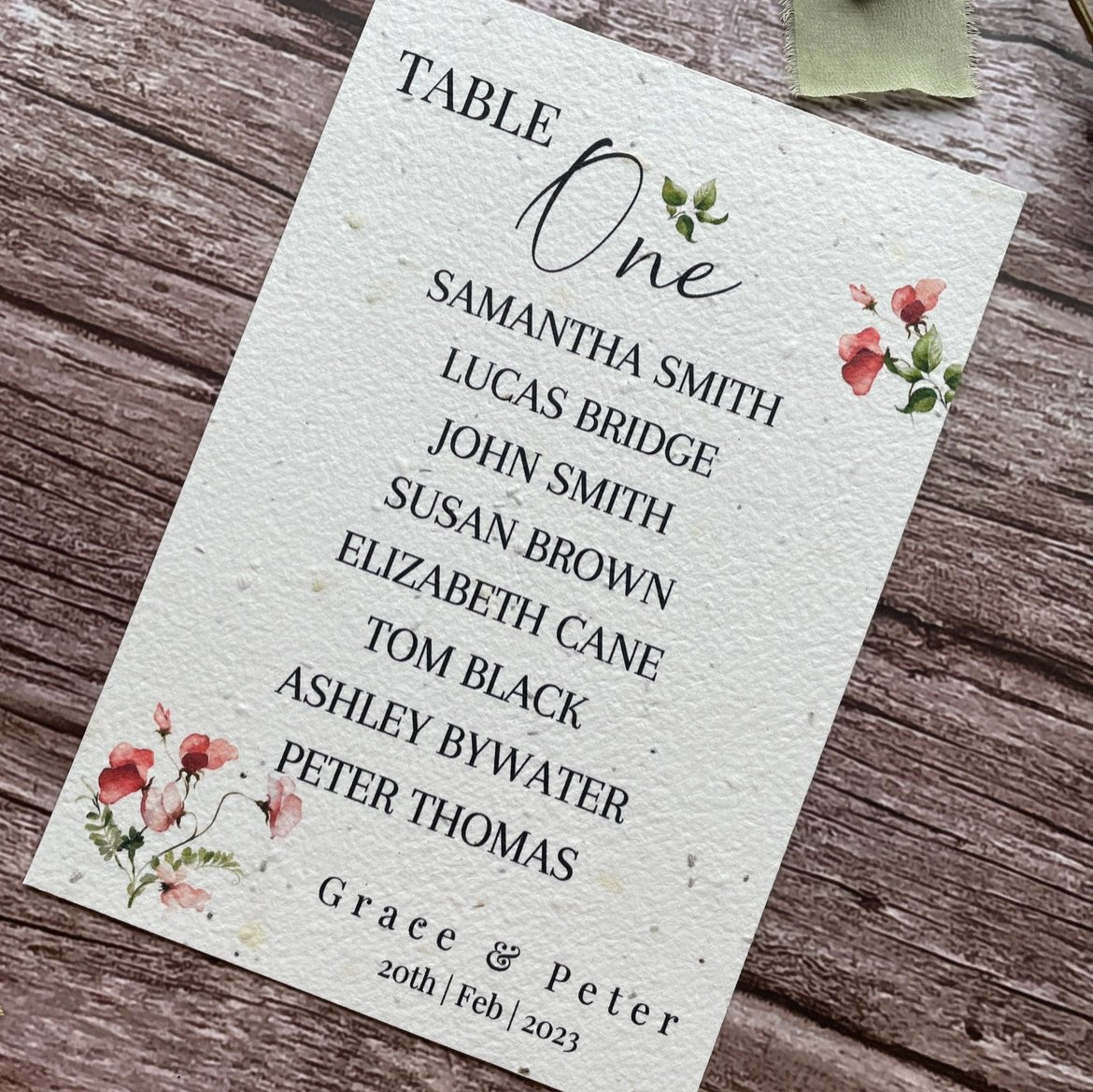 plantable seed paper wedding table seating plan in sweet pea theme, angled right view with floral design on wooden background, eco-friendly, alakartcreations