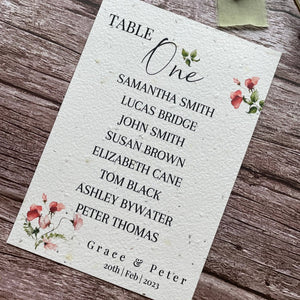 plantable seed paper wedding table seating plan in sweet pea theme, showing angled right view, floral design on wooden background, eco-friendly