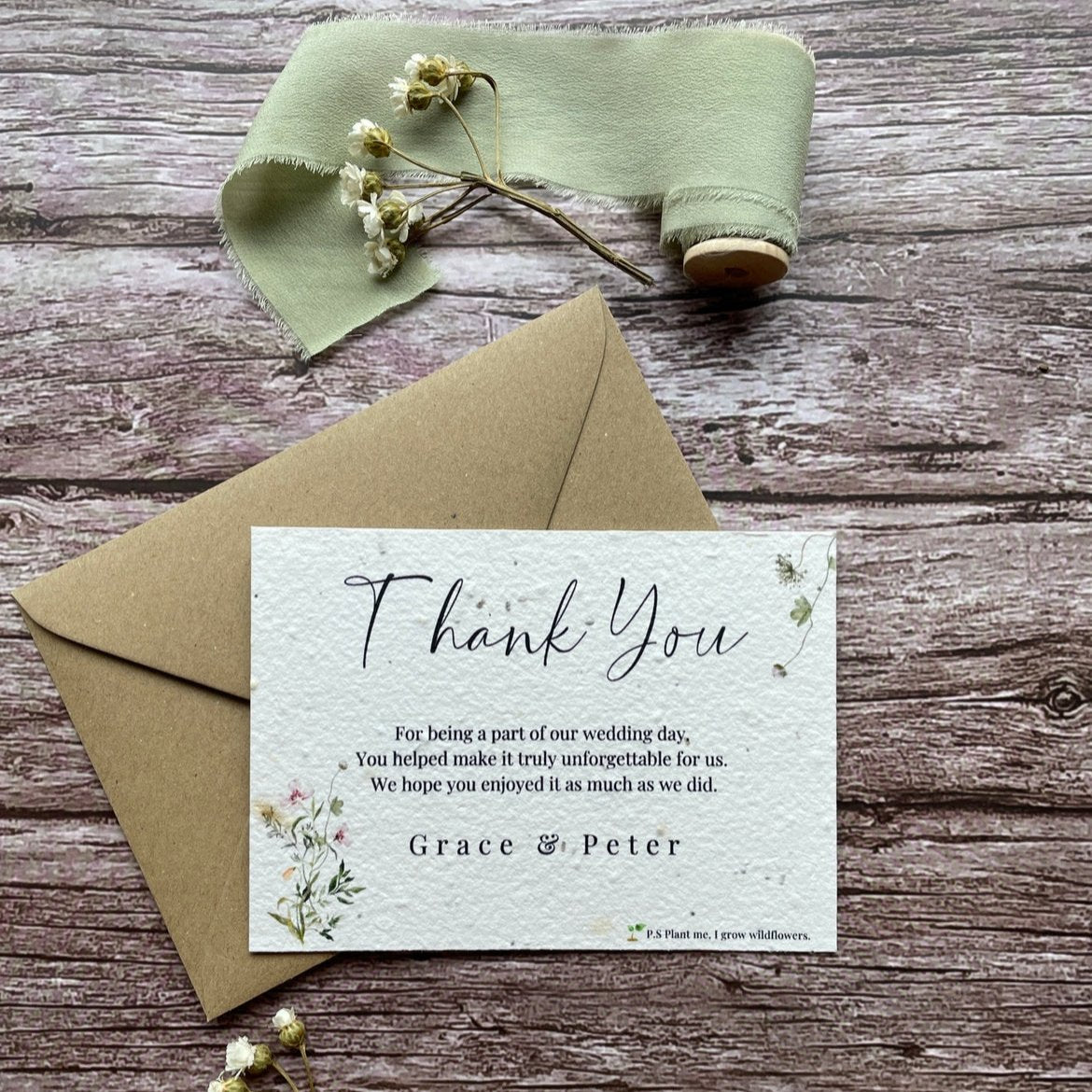 plantable seed paper wedding thank you cards with botanical design, front view with eco-friendly brown kraft envelope on wooden background