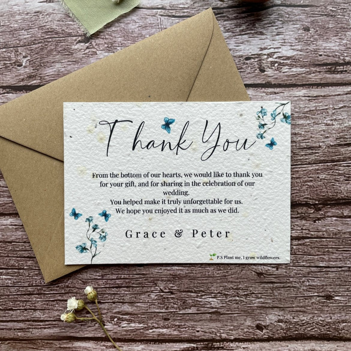 plantable seed paper wedding thank you cards dusty blue theme, front view with eco-friendly brown kraft envelope, floral design on wooden background