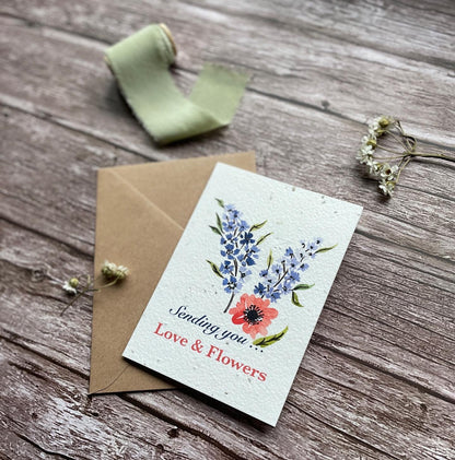 seed paper sending you love and flowers card with blue delphiniums on a wooden surface